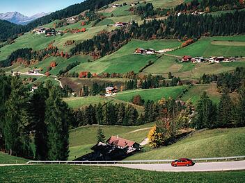 Abenteuertour mit dem Auto auf der Bergstra&szlig;e gegen gr&uuml;ne Almwiesen in den italienischen Dolomiten, Funes-Tal, Trentino S&uuml;dtirol, Italien im Herbst  Adventure trip by car on mountain road against alpine green meadows in Italian Dolomites Alps, Funes Valley, Trentino Alto Adige, Italy in autumn