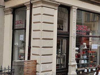 Geschäft in der Bamberger Altstadt, „Eberl's Genusswelt“, wird geschlossen. Schaufenster zeigt Küchengeräte und Dekoartikel, Menschen vorbeigehend. Historische Fassade.