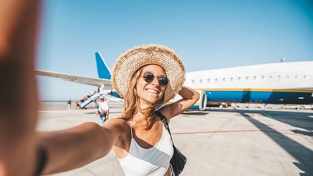gl&uuml;ckliche Frau, die am Flughafen vor dem Flugzeug ein Selfie macht. Menschen beim Abflug, Boarding, Urlaubskonzept. Flugreise Urlaub Reise