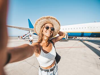 Sicher fliegen: Warum kurze Kleidung keine gute Idee ist glückliche Frau, die am Flughafen vor dem Flugzeug ein Selfie macht. Menschen beim Abflug, Boarding, Urlaubskonzept. Flugreise Urlaub Reise