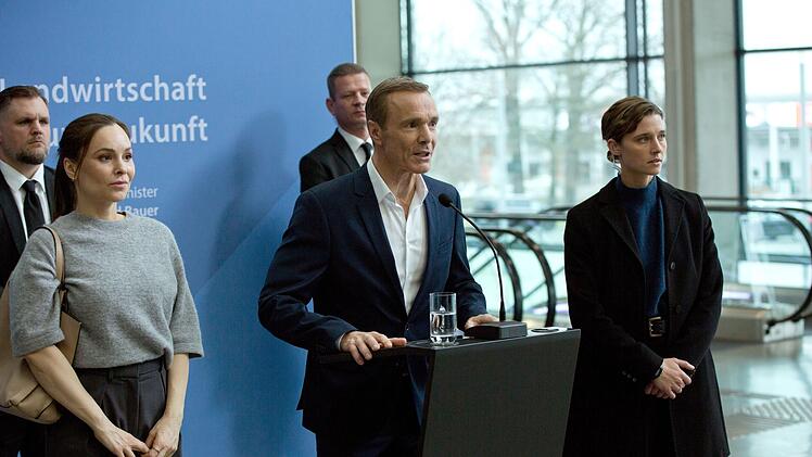 Wirtschafts- und Umweltminister Bauer (Hannes Jaenicke, zweiter von rechts) wird bei einer Rede angegriffen, Personensch&uuml;tzerin Helen Schilling (Svenja Jung, rechts) kann nicht viel tun.