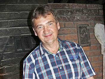 Andreas Weiß steht vor seinem Backofen und hält eines seiner Brote in der Hand. Er bäckt es aus selbst angebautem Roggen. Weiß ist als Stadtrat für die Freien Wähler nachgerückt. Foto: Tobias Kindermann