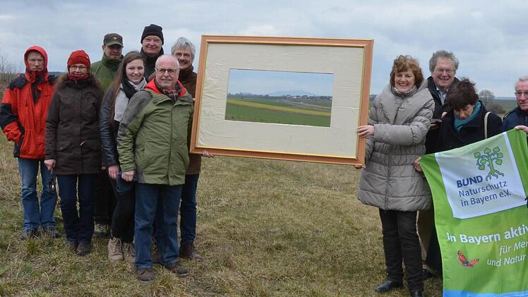 Mitglieder des Bundes Naturschutz und Gegner des neuen Flugplatzes fokussieren mit einem Bilderrahmen den Blick auf das Gelände, auf dem der neue Landeplatz gebaut werden soll. Foto: Rainer Lutz