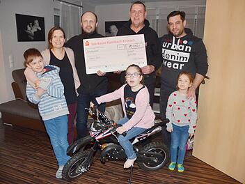Der Royal-Enfield-Club Kronach spendet 10 000 Euro für ein Zimmer für die schwer kranke Milah (vorne, auf ihrem Motorrad) und macht eine ganze Familie glücklich. Das Bild zeigt von links Sohn Noah, Mutter Christina Weber, Jörg Köstner, Lothar Franz (beide Royal-Enfield-Club), Vater Marius Weber und Tochter Emma bei der Übergabe des symbolischen Schecks. Foto: Karl-Heinz Hofmann