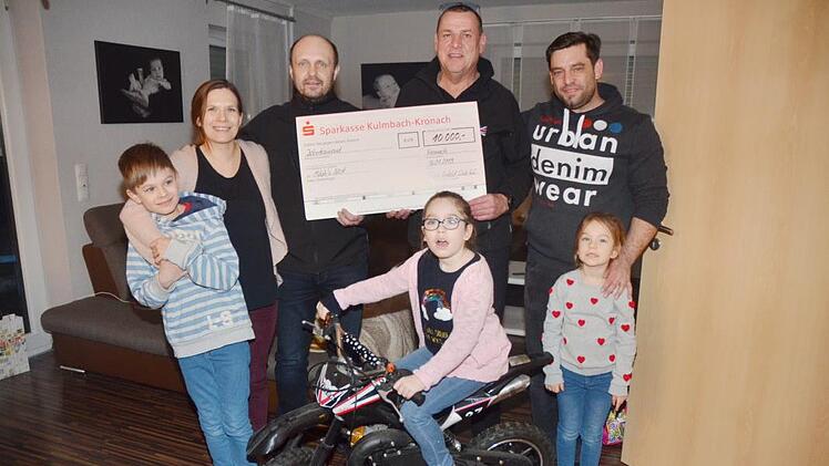 Der Royal-Enfield-Club Kronach spendet 10 000 Euro für ein Zimmer für die schwer kranke Milah (vorne, auf ihrem Motorrad) und macht eine ganze Familie glücklich. Das Bild zeigt von links Sohn Noah, Mutter Christina Weber, Jörg Köstner, Lothar Franz (beide Royal-Enfield-Club), Vater Marius Weber und Tochter Emma bei der Übergabe des symbolischen Schecks. Foto: Karl-Heinz Hofmann