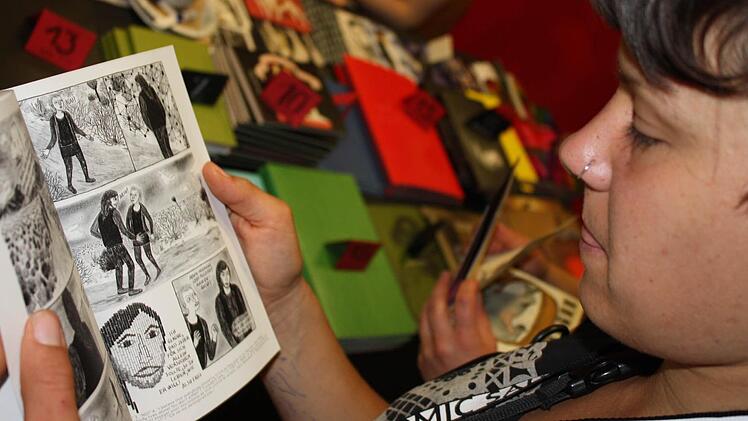 Die Comiczeichnerin Marlene Krause blättert in ihrem Buch "Choking on heroes".