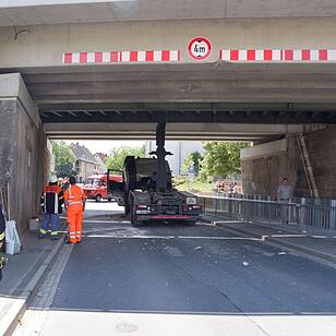 Lkw mit Kranaufbau fährt sich unter Brücke fest