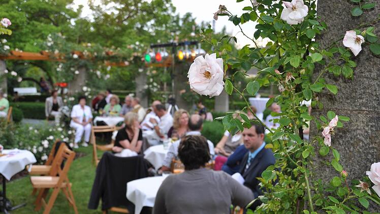 Der Rosengarten in der Promenade in Ha&szlig;furt bot eine stimmungsvolle Atmosph&auml;re f&uuml;r das Konzert am Wochenende. Die Besucher, hier die Familien Br&uuml;ckner und Krieger,  genossen die Darbietungen im Freien. Foto: ul