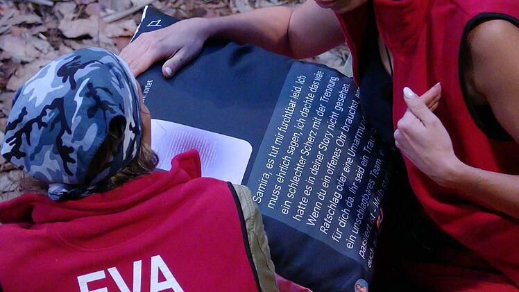 Samira hat Evas Nachricht auf ein Kissen drucken lassen, die sie w&uuml;tend vorliest.