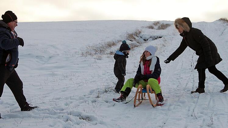 Die Kinder Lina und Sören haben viel Spaß beim Schlittenfahren. Die Erwachsenen leisten Hilfestellung und sorgen für den nötigen Schwung, wenn es auf dem Schnee dahingeht.