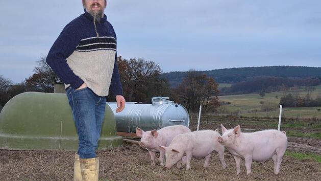 Burkard Mahlmeister aus Stangenroth vermarktet seit 1993 sein erzeugtes Fleisch und die selbst produzierten Wurstwaren selbst. Hier steht er in einem Freilandgehege seines Hofs, in dem diese drei Schweine zu Hause sind.  Foto: Kathrin Kupka-Hahn