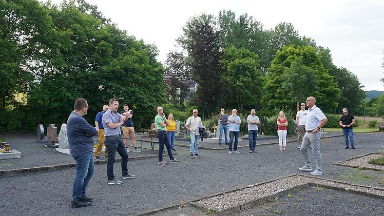 Der Friedhof in der Reußendorferstraße Wildflecken soll mehr pflegeleichtes Grün bekommen, das gemäht werden kann. Die Gemeinderätinnen und -räte schauen sich den Friedhof bei einem Ortstermin mit Bürgermeister Gerd Kleinhenz an. Foto: Marion Eckert
