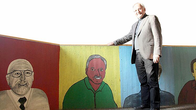 Ist noch wieder zu erkennen: Johann Püttner kniet im Treppenaufgang neben seinem Porträt. Vor knapp 17 Jahren wurden die Lehrer künstlerisch verewigt.