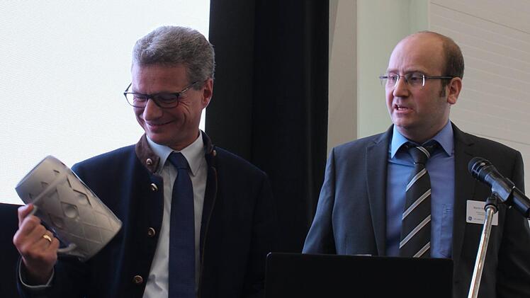 Standortchef Martin Hofmann (rechts) von GE Additive Lichtenfels überreichte Minister Sibler einen aus Titan im 3D-Verfahren gefertigten Krug.