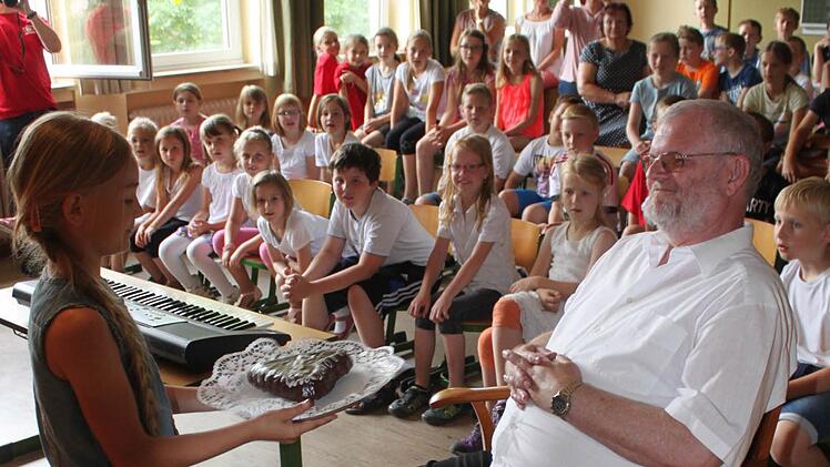 Magdalena aus der zweiten Klasse überreicht Michael Barnickel einen Kuchen. Foto: Gerd Klemenz