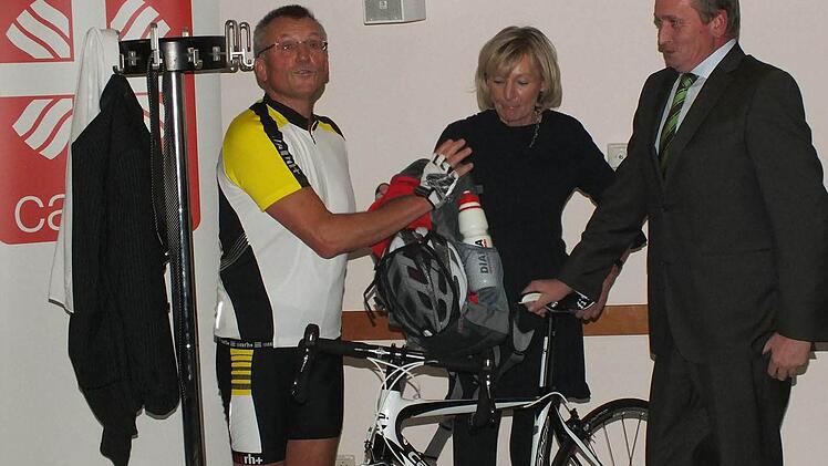 Johann Brandt (l.) war scheinbar darauf vorbereitet, dass er zum Abschied ein Rennrad bekam, den er trug sein Radleroutfit unter dem Anzug. Edith Scherbel für die Mitarbeiter und Brandts Nachfolger Markus Beck überreichten ihm das Geschenk. Foto: Manfred Welker
