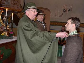 Er ist derzeit der jüngste unter den Jungjägern der Kreisgruppe Kronach. Der 19-jährige Christian Ebert (rechts) erhält den Jägerschlag durch Ehrenmitglied Alexander Lücker (links). Mit im Bild, der Kreisvorsitzende Bernhard Schmitt (2.v.l.), im Hintergrund sitzend, Regionaldekan Thomas Teuchgräber, selbst auch passionierter Jäger.