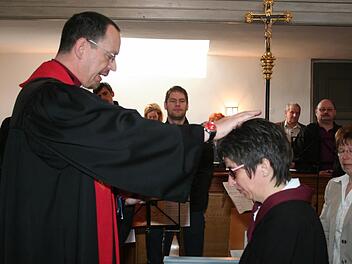 Pfarrer Torsten Bader segnet die neue Lektorin Michaela Wüst durch Handauflegung. Foto: Evi Seeger
