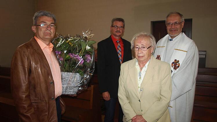 Sich um die Grotte zu kümmern, ist seit 50 Jahren für Regina Schmitt ein Herzensanliegen. Bei einer Marienandacht in der Kirche dankten ihr dafür Pfarrer Edwin Ziegler (rechts), Kirchenpfleger Klaus Kiesel (links) und Roland Seufert für den Pfarrgemeinderat.  Foto: Stefan Geiger