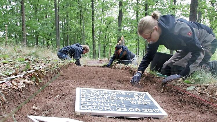 Studenten der Archäologie bei der Arbeit: Alexander Pelz, Daniela Blase (von links) und Julia Stiene (vorne) tragen die oberste Bodenschicht vorsichtig ab. Die Randscherbe eines Tongefäßes kam sogleich zu Beginn zum Vorschein, die genaue Untersuchung des Fundstückes erfolgt aber erst an der Universität in Bamberg - gesicherte Ergebnisse lassen also noch etwas auf sich warten.  Fotos: Andreas Lösch