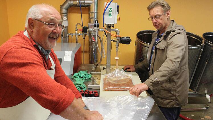 Klaus Andrae (links) und Hermann Schnupp füllen den Saft in Fünf- oder Zehn-Liter-Beutel ab.