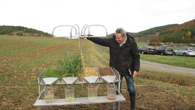 Vorf&uuml;hrung Regensimulator: Rainer Schubert demonstriert anhand des Regensimulators den unterschiedlichen Eintrag von Sedimenten ins Gew&auml;sser, auf Gr&uuml;nland, Zwischenfruchtbest&auml;nden, mit einer Mulchauflage und "braunem" unbestellten Feld.  Fotos: Julian Megner/ AELF