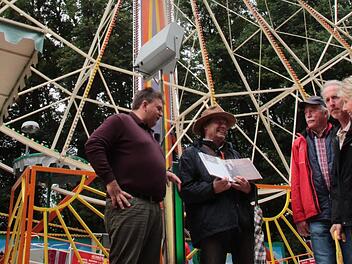 Am Riesenrad von Michael Drliczek (links) zeigt Jürgen Zöbelein (Mitte mit Buch) das Annafest-Buch von 2015 und erzählt die Geschichte des Riesenrads. Foto: Jennifer Hauser