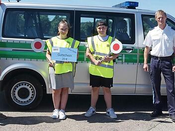 Die beiden Verkehrserzieher der Polizeiinspektion Ha&szlig;furt , Dominique Heim (rechts) und Matthias Krapf (Zweiter von rechts), &uuml;berreichten den beiden Sch&uuml;lerlotsen der Waldorfschule, Lorena Hertinger und Jakob Zehendner, stellvertretend f&uuml;r alle anderen freiwillig Engagierten im Landkreis die von der Kreisverkehrswacht Ha&szlig;berge gesponsorten Warengutscheine; links Lehrer Walter-Johannes Pirling. Foto: Christian Licha