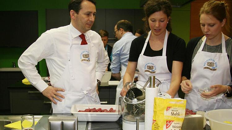 Otto Zejmon, Maria Krieger und Daniela Prestele wälzen Kartoffeln in geschrotetem Malz.