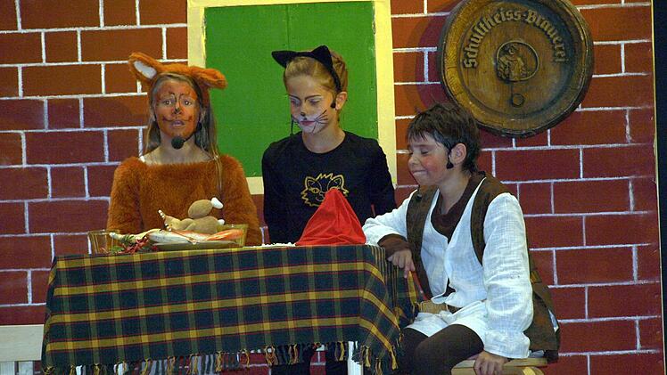 Die listige Füchsin (Janina Hellgeth, links) und der schlaue Kater (Emma Köstner, rechts) kehren auf Kosten von Pinocchio (Katrin Schnell) in der Taverne ein.