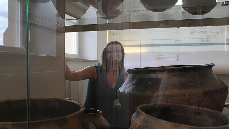 Museumsleiterin Adelheid Waschka kniet hinter einer Vitrine mit Keramikgefäßen.