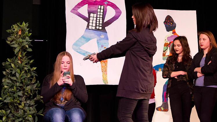Laura (Xenia-Laura Miener) ist an ihrem Smartphone und bekommt während des Experiments nicht mal mit, wie Jacky (Lea Schneider) ihr testweise mit einer Waffe droht