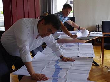 Bürgermeister Jens Korn (links) und Frank Jakob von der Stadtverwaltung reihen die Pläne für die Stadt Wallenfels auf. Das obere Bild zeigt einen Ausschnitt mit den Flächen (blau), auf die sich ein hundertjähriges Hochwasser den Berechnungen nach auswirken würde. Foto: Marco Meißner