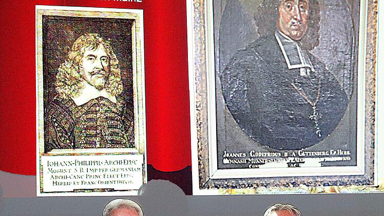 Die Stuckdecke der Alten Aula stand im Mittelpunkt eines Vortrags von Franz  Gopp (links). Die Fotos dazu machte Bruno Schlegelmilch (rechts). Im  Hintergrund Abbildungen der Fürstbischöfe Johann Philipp von Schönborn und     Johann Gottfried II. zu Guttenberg. Foto: Dieter Britz
