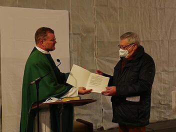 Erhard Ledermann  nimmt als Vertreter der Laien die Errichtungsurkunde für den Pastoralen Raum Münnerstadt aus den Händen von Generalvikar Jürgen Vorndran entgegen. Foto: Heike Beudert