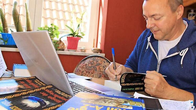 Werner Karl in seinem Wohnzimmer, wo er am Laptop seine Fantasy-Romane verfasst. Foto: Matthias Einwag