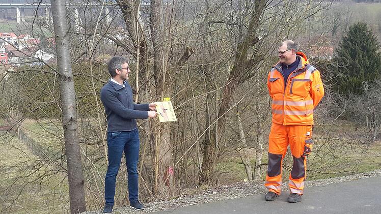 Symbolischer Startschuss für die Kennzeichnung neuer Habitatbäume: Bad Brückenaus Bürgermeister Jochen Vogel (links) hält vor dem entsprechenden Gehölz unter Beachtung des Corona-Abstands das erste Schild für Stadtgärtner Markus Bott parat. Foto: Rolf Pralle
