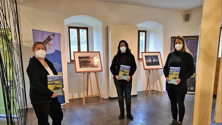 Im Bruder Franz Haus auf dem Kreuzberg ist noch bis Anfang M&auml;rz 2022  die Ausstellung "Mensch.Natur. Einklang." zu sehen. Von links: Carmen Zinssler-Maul und Janine L&ouml;hrlein, (Rh&ouml;n GmbH / Bruder Franz Haus) und Anna-Lena Bieneck (Hessische Verwaltung UNESCOBiosph&auml;renreservat Rh&ouml;n).