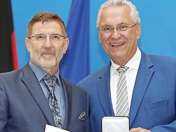 Michael Busch erh&auml;lt von Innenminister Joachim Herrmann die kommunale Verdienstmedaille.  Foto: Sammy Minkoff