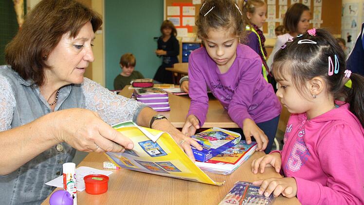 Lehrerin Marina Trümbach und Schulpatin Natalia aus der 2. Klasse helfen Erstklässlerin Amalia (rechts) beim Einräumen der Schulsachen.