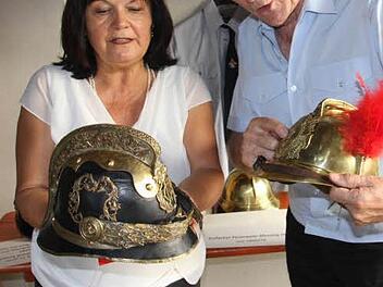 Gertrud Bühl und Ehrenkreisbrandinspektor Reiner Schuster fachsimpeln über alte Helme. Foto: Helmut Will