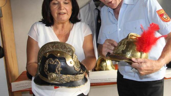 Gertrud Bühl und Ehrenkreisbrandinspektor Reiner Schuster fachsimpeln über alte Helme. Foto: Helmut Will