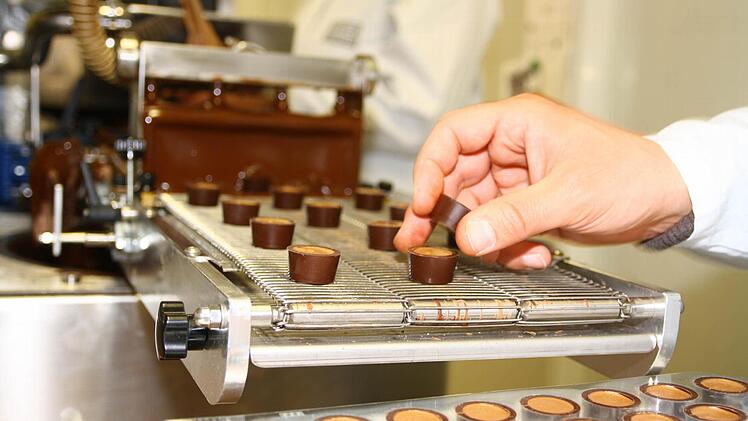 Von Hand werden die Pralinen zum Überziehen aufs Band gesetzt.