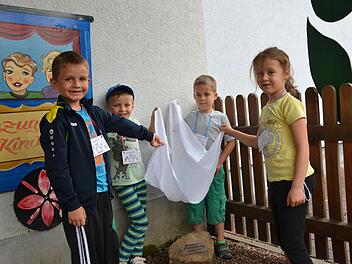 Alessio, Fabian, Felix und Laura (von links) enthüllen beim Putzenbräu-Gedenkfest im Garten des Kindergartens den Stein mit Inschrift, der daran erinnert, dass dort einmal eine Brauerei stand. Foto: Sandra Hackenberg