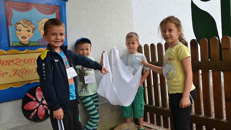 Alessio, Fabian, Felix und Laura (von links) enthüllen beim Putzenbräu-Gedenkfest im Garten des Kindergartens den Stein mit Inschrift, der daran erinnert, dass dort einmal eine Brauerei stand. Foto: Sandra Hackenberg