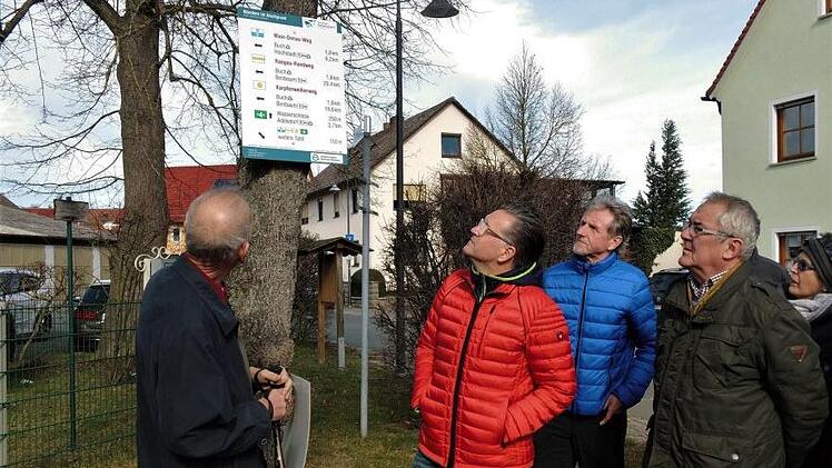 Andreas Schettler (l.) erklärt den Wanderern die Symbole auf der Hinweistafel.   Foto: Britta Schnake