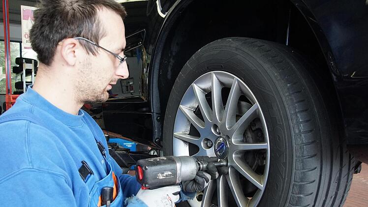 Michael Sewiolo schraubt in der Hammelburger Werkstatt einen Sommerreifen von einem Auto ab.  Arkadius Guzy