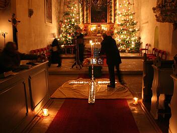 Gemeindemitglieder zünden in dem nur von Kerzen erleuchteten Gotteshaus Lichter an und stellen sie auf ein ausgelegtes Kreuz,.  Foto: Evi Seeger