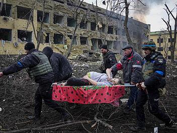 Ukrainische Rettungskräfte und Freiwillige tragen eine verletzte Schwangere aus einer Entbindungsklinik, die durch Beschuss in Mariupol beschädigt wurde.