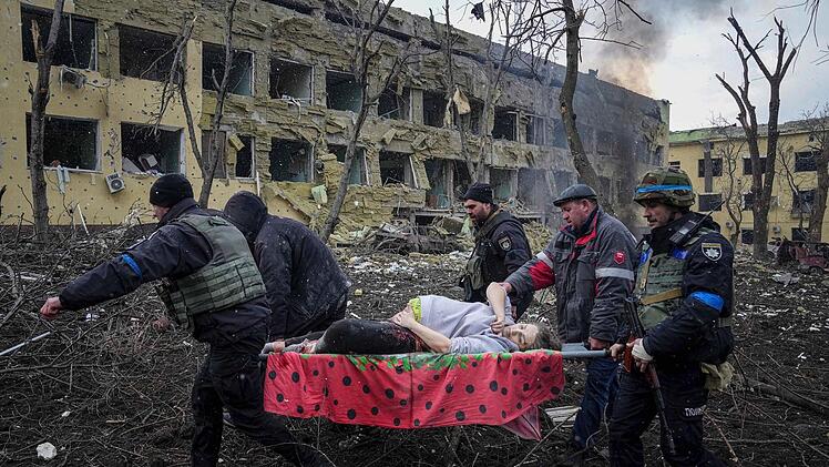 Ukrainische Rettungskräfte und Freiwillige tragen eine verletzte Schwangere aus einer Entbindungsklinik, die durch Beschuss in Mariupol beschädigt wurde.